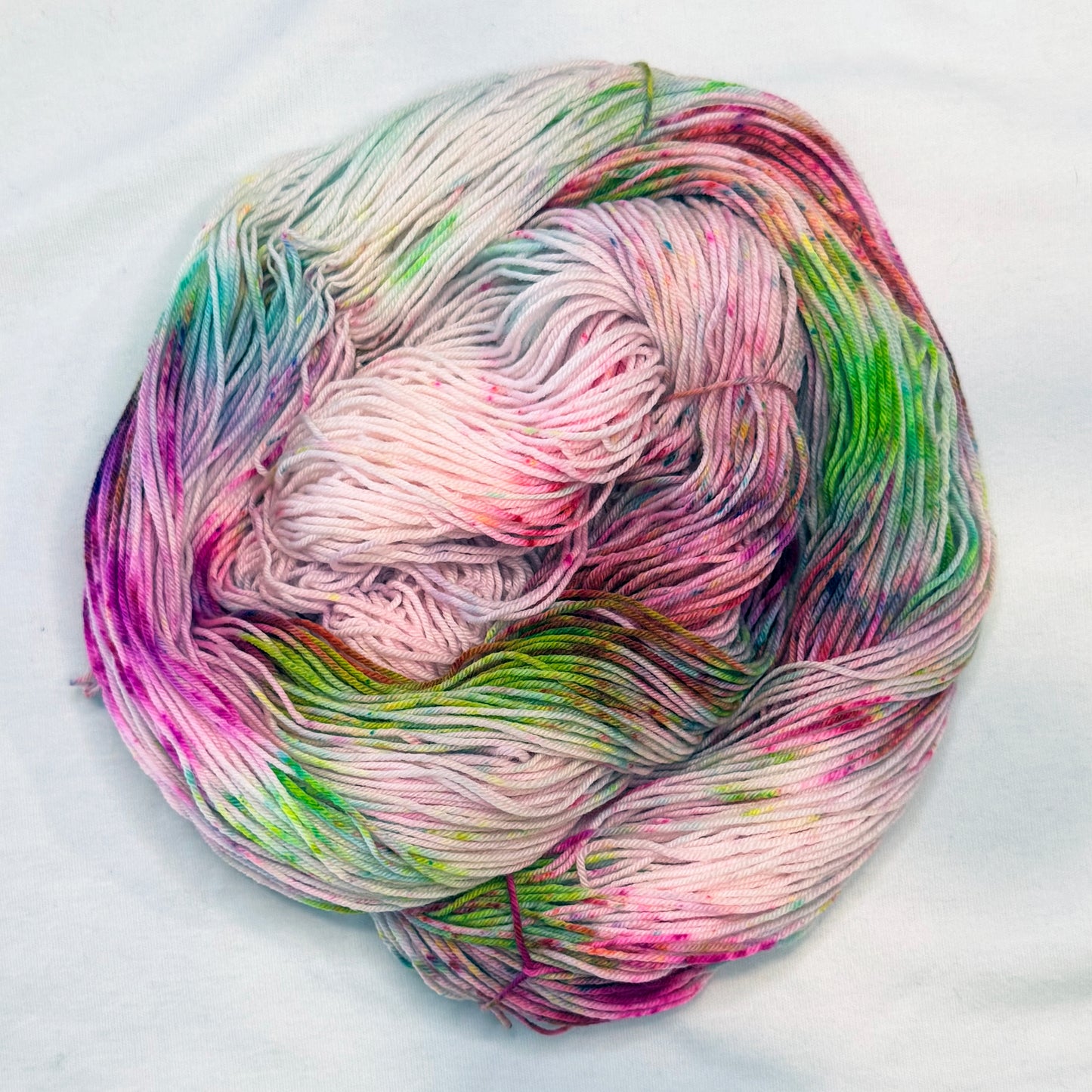 Hand-dyed yarn in soft cream with bright speckles of pink, lime, and magenta — playful, floral, and full of spring sparkle.
