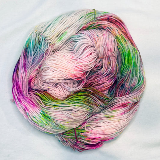 Hand-dyed yarn in soft cream with bright speckles of pink, lime, and magenta — playful, floral, and full of spring sparkle.