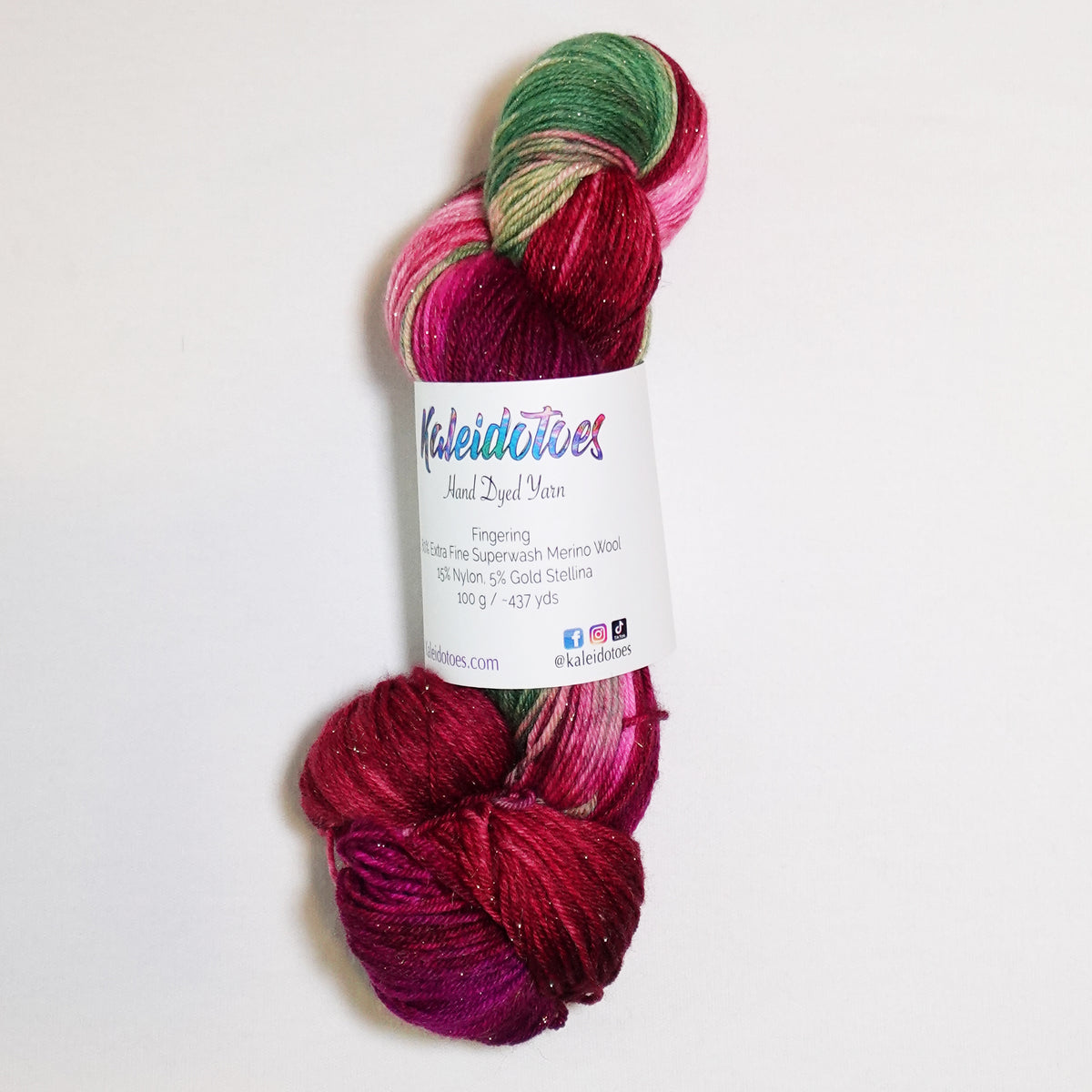 Hand-dyed gold metallic fingering weight yarn in rich crimson, deep berry and leafy green with a fine gold metallic thread.