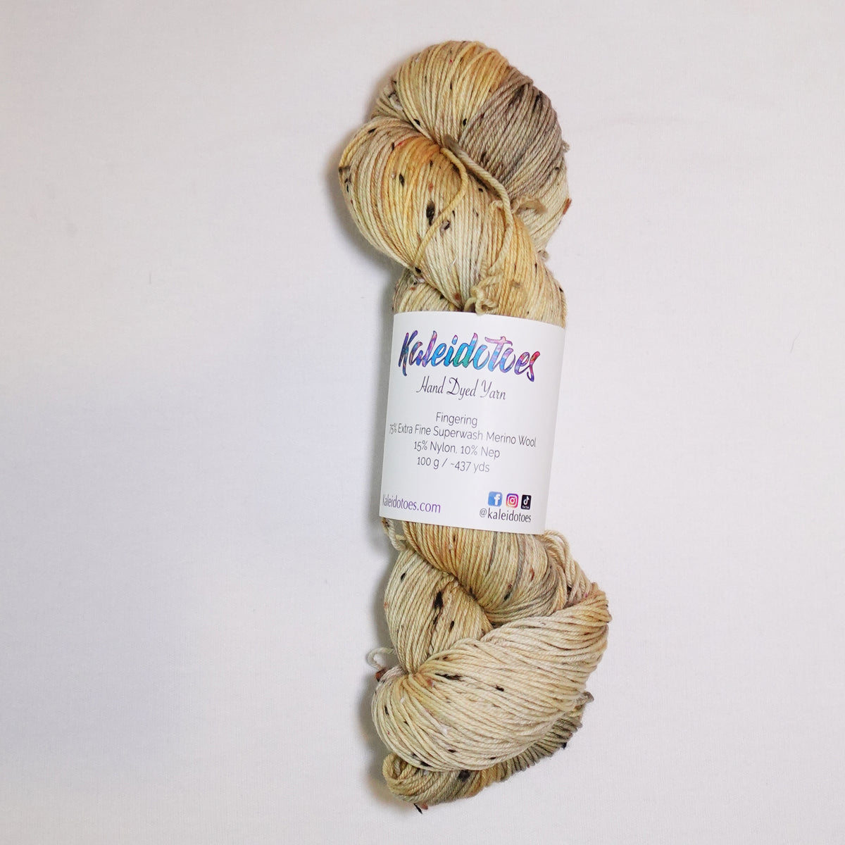Hand-dyed tweed fingering weight yarn in weathered gold, straw, cream and soft tan with black tweed flecks.