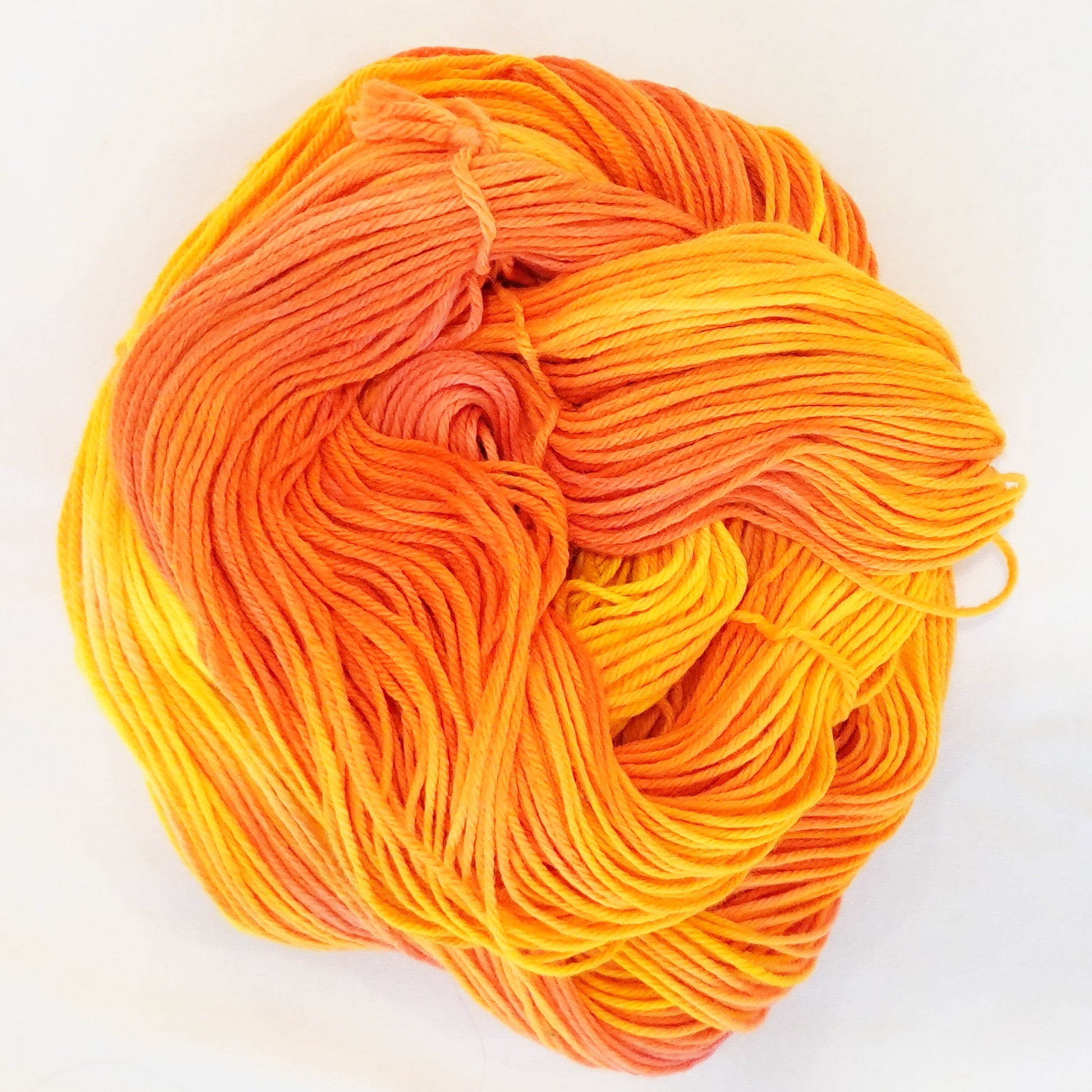 Hand-dyed DK weight yarn in golden yellow, tangerine, and blazing orange - vivid, saturated, and unapologetically bright.