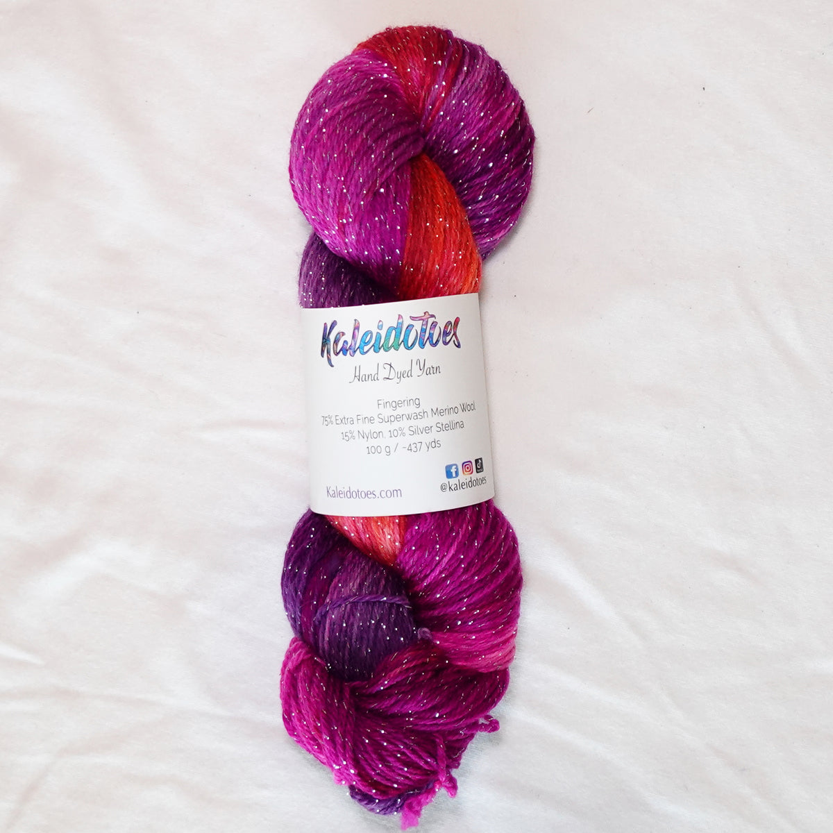 House Sangria hand-dyed fingering weight yarn in rich wine purple, berry pink and red-orange with a fine silver metallic thread.