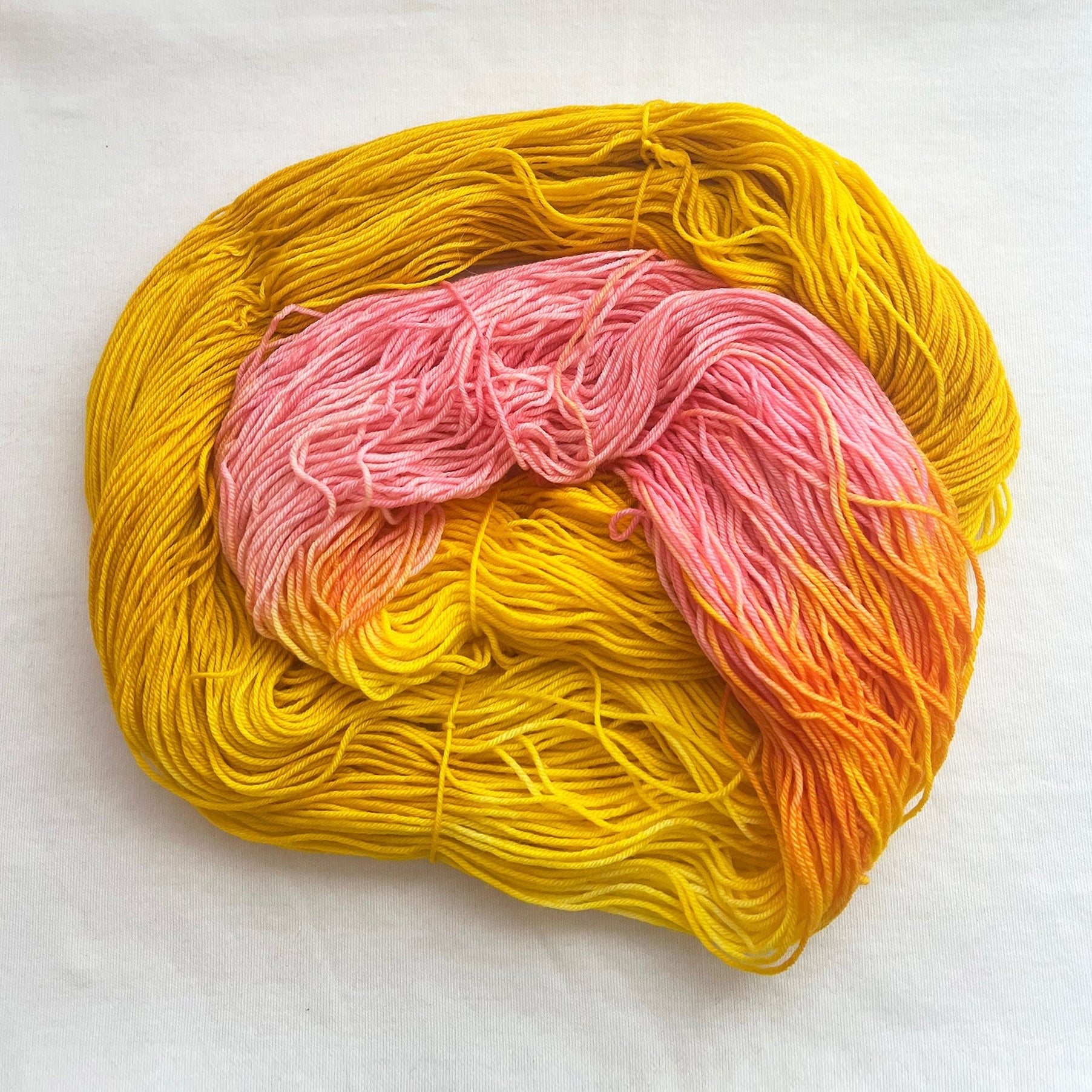 Superwash merino fingering weight yarn, variegated golden yellow with soft pink accents