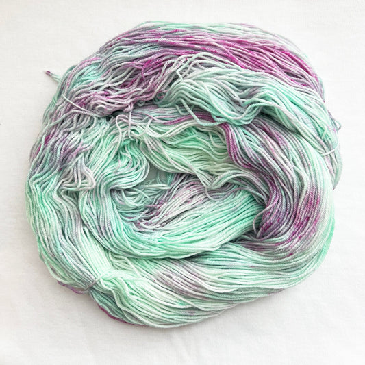 Hand-dyed sock yarn in mint green with lilac highlights and pink speckles