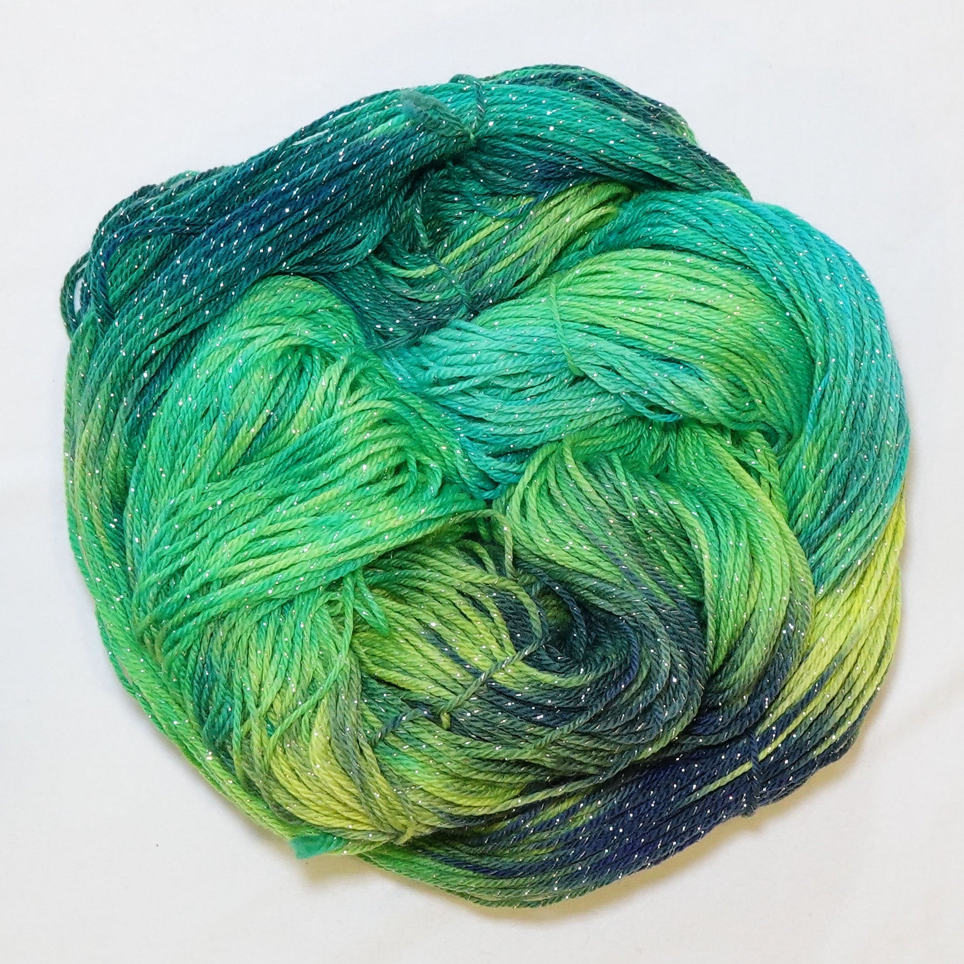 Hand-dyed fingering weight yarn in electric lime, chartreuse, emerald, and turquoise with navy shadows and silver metallic thread throughout.