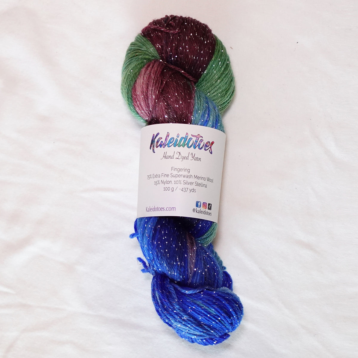 Long Weekend hand-dyed fingering weight yarn in saturated blue, layered greens and rich wine-plum with a fine silver metallic thread.