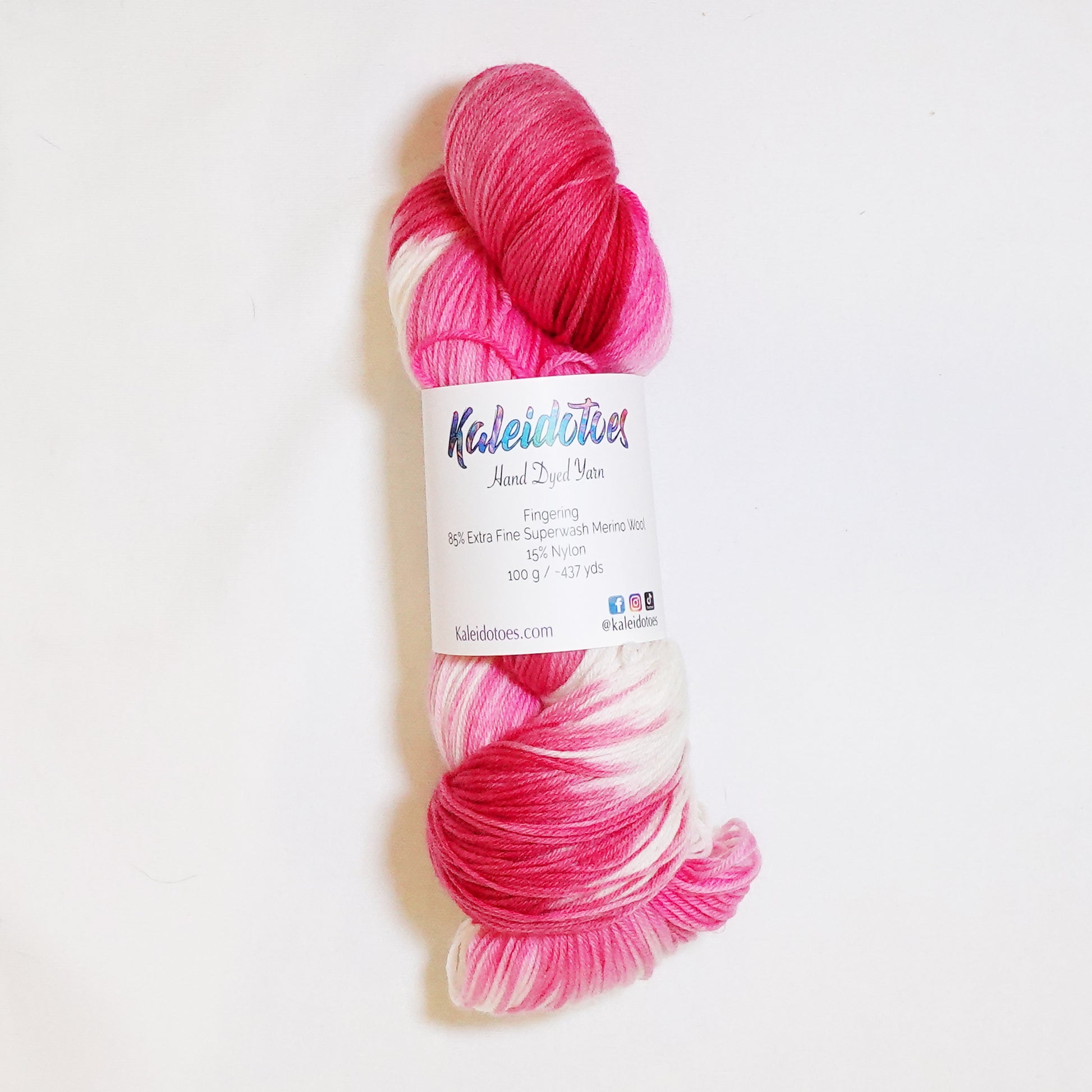 Hand-dyed fingering weight yarn in deep red, hot pink, and white with sweeping color transitions throughout.
