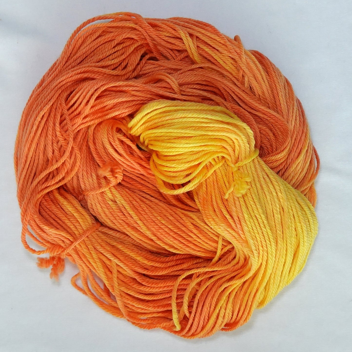 Hand-dyed worsted weight yarn in deep persimmon, tangerine, and saturated yellow with a warm tonal gradient throughout.