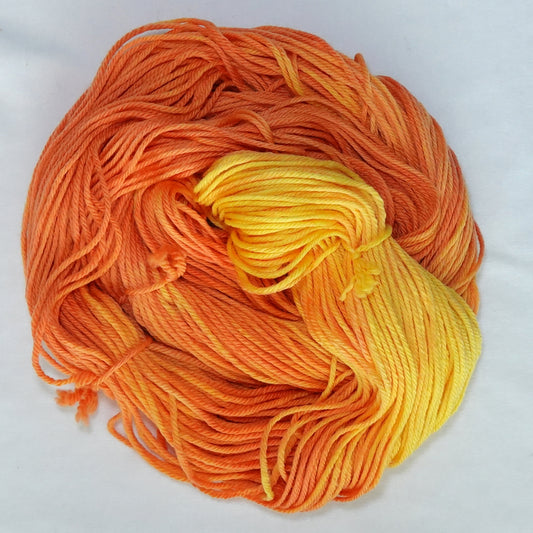 Hand-dyed worsted weight yarn in deep persimmon, tangerine, and saturated yellow with a warm tonal gradient throughout.