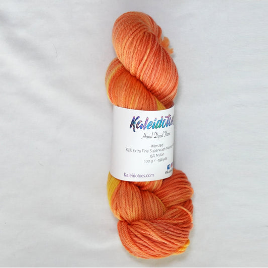 Hand-dyed worsted weight yarn in deep persimmon, tangerine, and saturated yellow with a warm tonal gradient throughout.