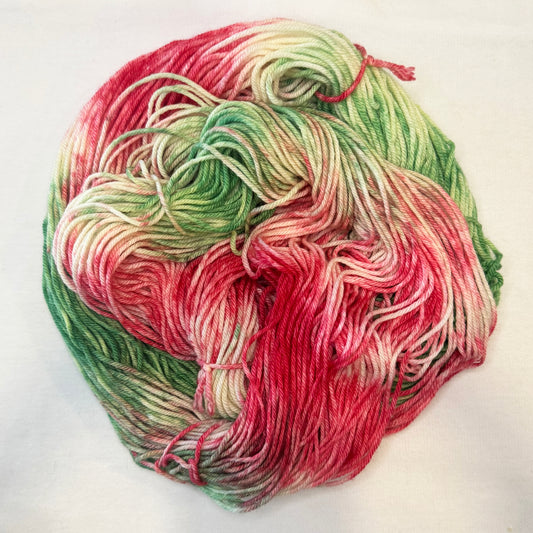 Hand-dyed yarn in shades of evergreen, crimson, and ivory — festive and playful like holiday ribbons intertwined.
