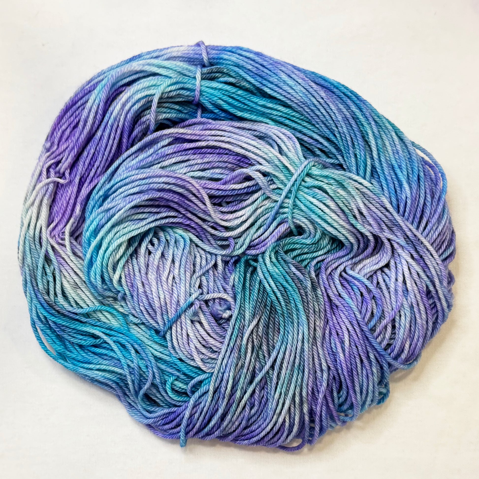 Hand-dyed yarn in teal, blue, and violet tones with touches of black, inspired by icy glacial colors.