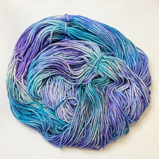 Hand-dyed yarn in teal, blue, and violet tones with touches of black, inspired by icy glacial colors.