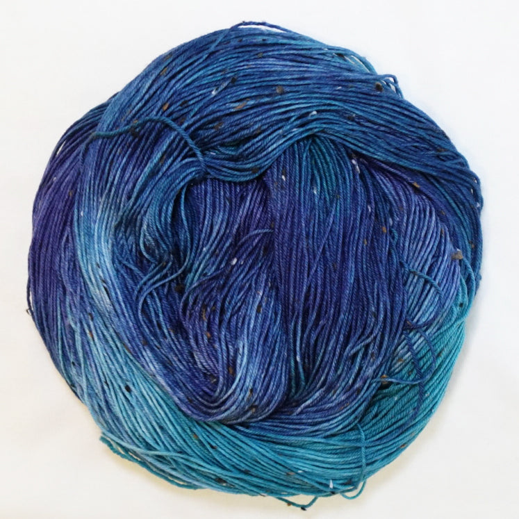 Hand-dyed tweed fingering weight yarn in teal green, rich blue and deep navy with contrasting tweed flecks.