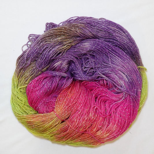 Hand-dyed fingering weight yarn in chartreuse, coral, hot pink, magenta, and violet with silver metallic thread and scattered white patches throughout.