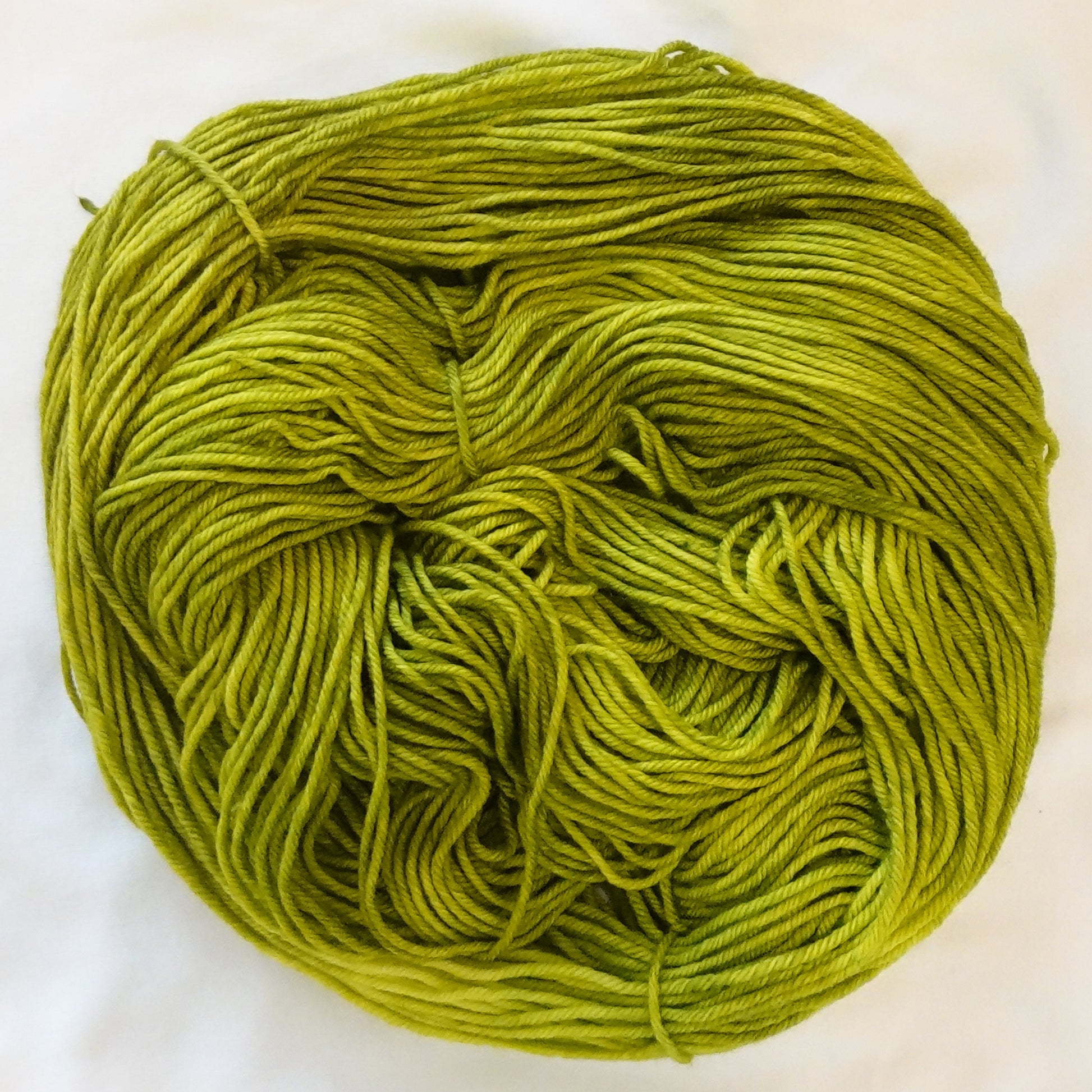 Hand-dyed yarn in vivid peridot green with subtle golden-yellow undertones and bright jewel clarity, inspired by Ra, the Egyptian sun god.