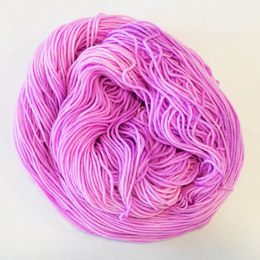 Hand-dyed yarn skein in layered cool pink tones ranging from pale blush to deeper petal pink