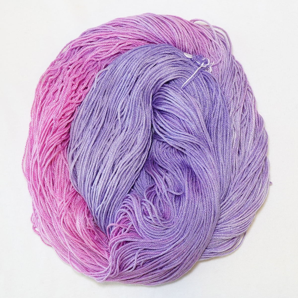 Hand-dyed fingering weight yarn in petal pink and soft lilac with a soft tonal fade.