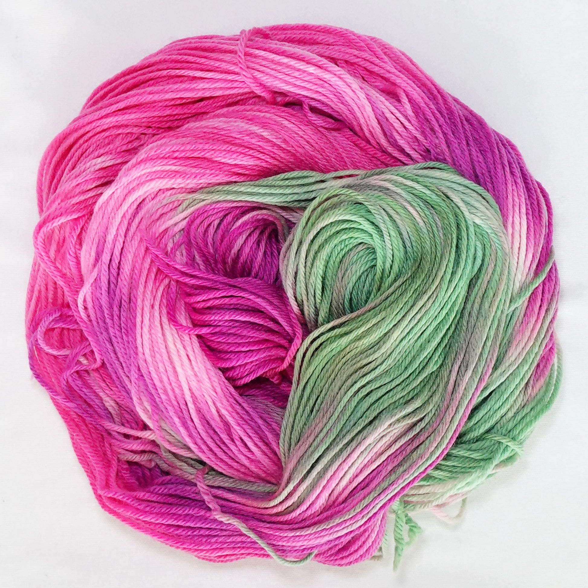 Hand-dyed worsted weight yarn in vivid magenta, soft pink, sage green, and white.