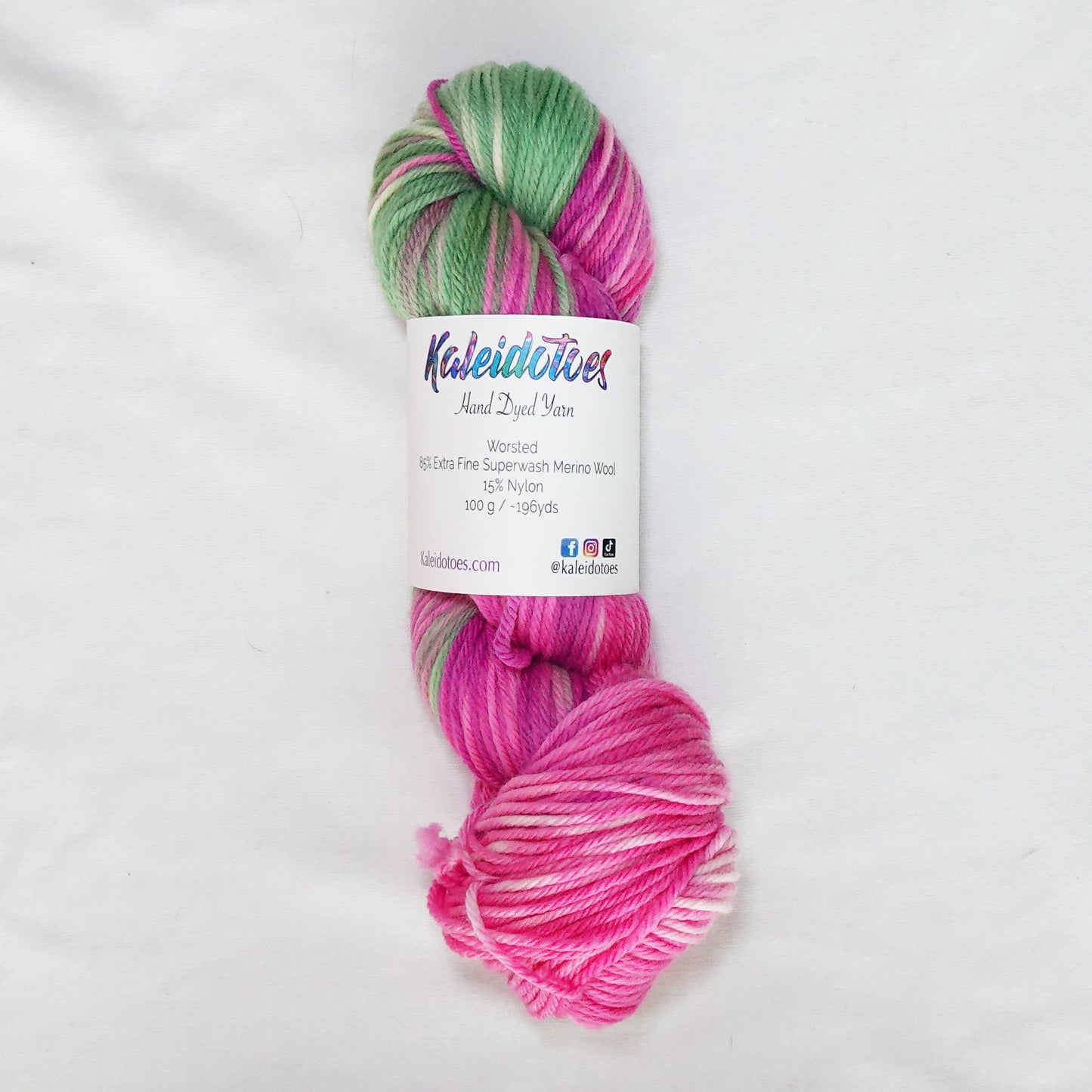 Hand-dyed worsted weight yarn in vivid magenta, soft pink, sage green, and white.