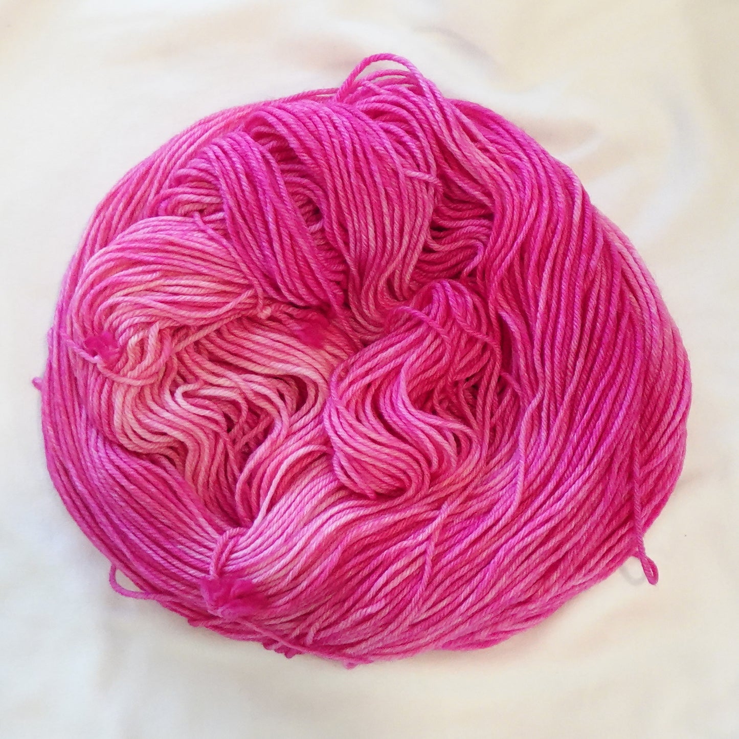 Hand-dyed yarn in vibrant pink tourmaline tones with saturated jewel depth and radiant tonal variation, inspired by the Egyptian goddess Isis.
