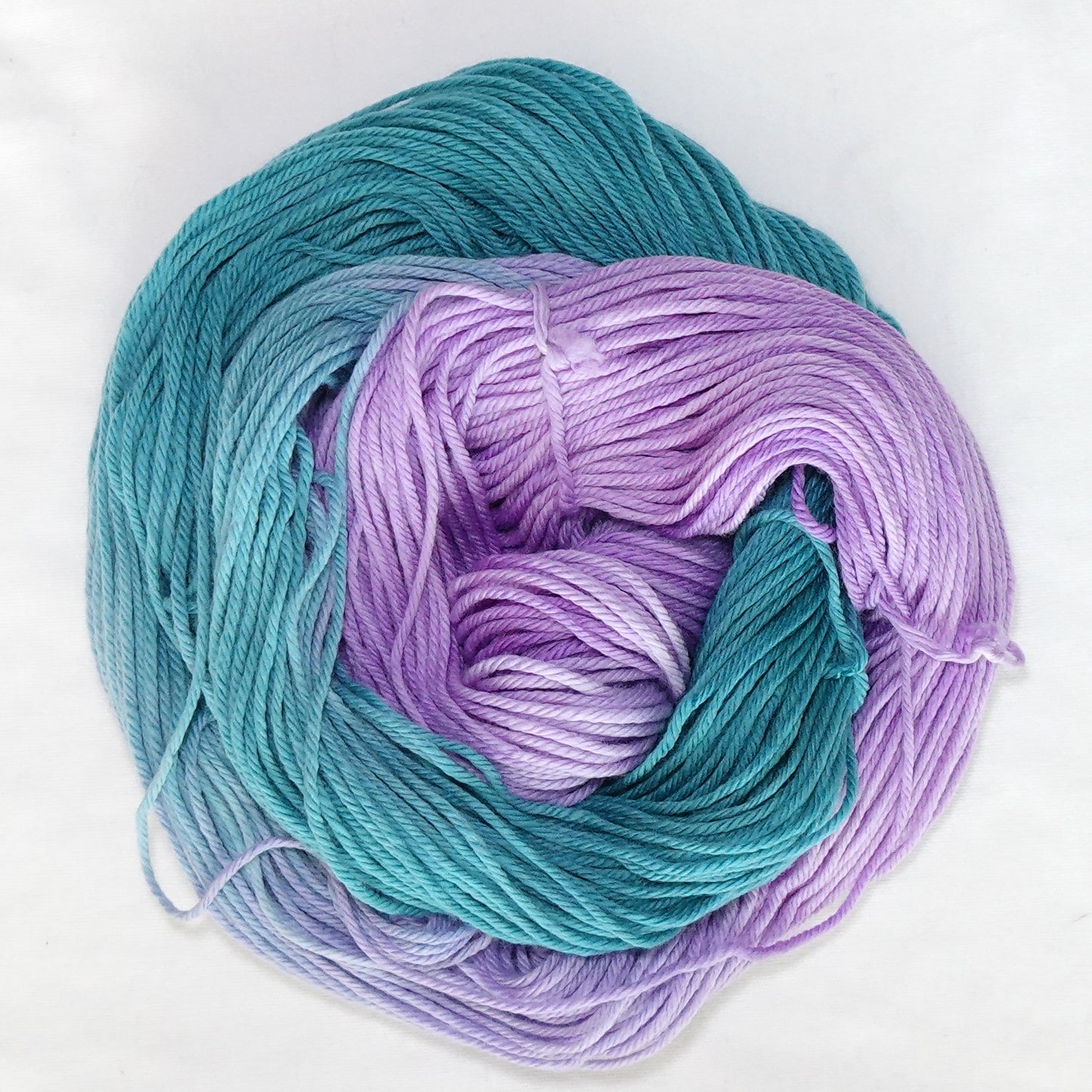 Hand-dyed worsted weight yarn in deep teal and bright purple with a clean transition where the two colors meet.