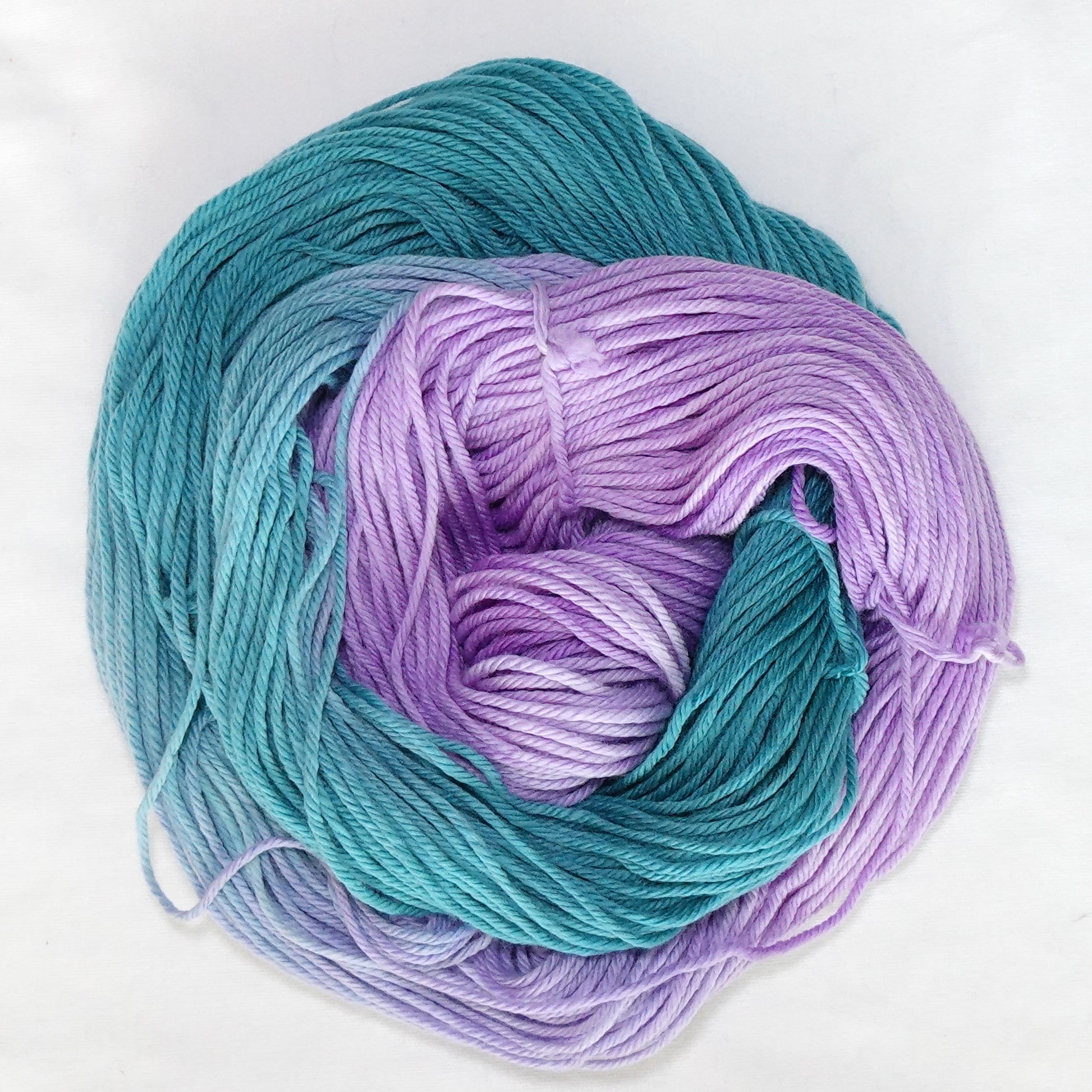 Hand-dyed worsted weight yarn in deep teal and bright purple with a clean transition where the two colors meet.
