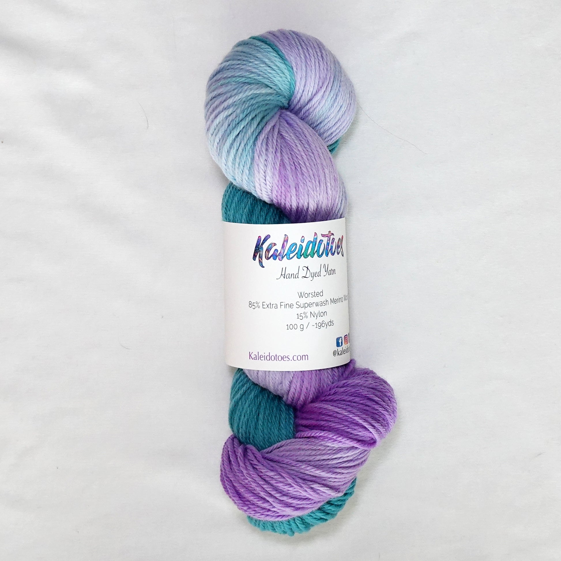 Hand-dyed worsted weight yarn in deep teal and bright purple with a clean transition where the two colors meet.