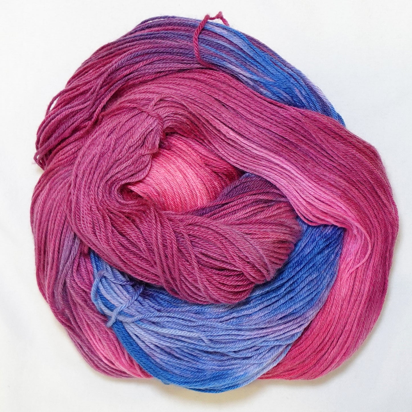 Hand-dyed fingering weight yarn in hot magenta, deep berry, and periwinkle blue with rich saturated color transitions throughout.