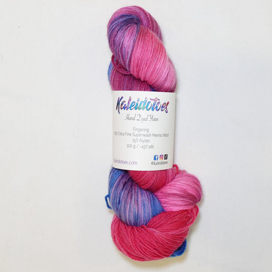 Hand-dyed fingering weight yarn in hot magenta, deep berry, and periwinkle blue with rich saturated color transitions throughout.