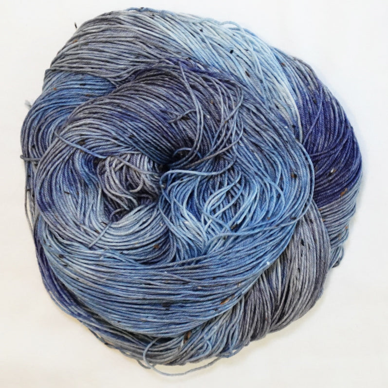 Hand-dyed tweed fingering weight yarn in rain-washed blue, slate grey and deep blue-grey with black tweed flecks.
