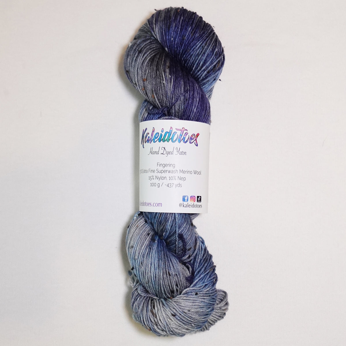 Hand-dyed tweed fingering weight yarn in rain-washed blue, slate grey and deep blue-grey with black tweed flecks.