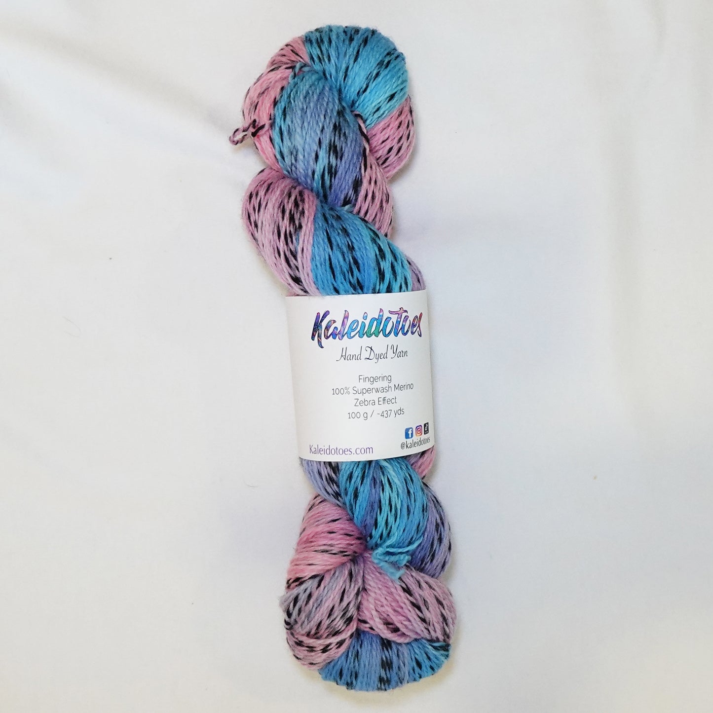 Hand-dyed fingering weight yarn in soft sky blue and rose pink with black twisted through and a hazy lavender where the colors meet.