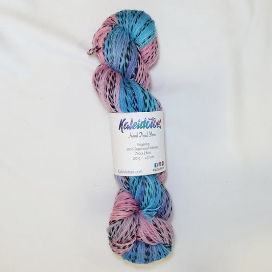 Hand-dyed fingering weight yarn in soft sky blue and rose pink with black twisted through and a hazy lavender where the colors meet.