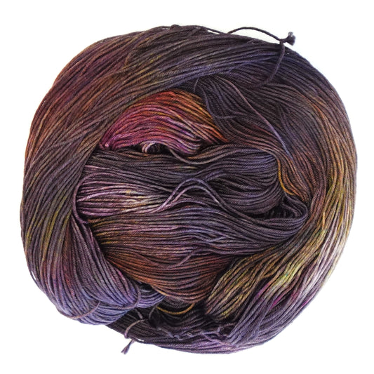 Hand-dyed fingering weight yarn in deep plum, smoky violet, rust, amber, and magenta with shadowy tonal depth throughout.