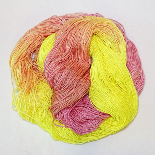 Hand-dyed fingering weight yarn in neon highlighter yellow, hot pink, and coral orange.