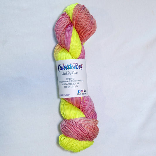 Hand-dyed fingering weight yarn in neon highlighter yellow, hot pink, and coral orange.