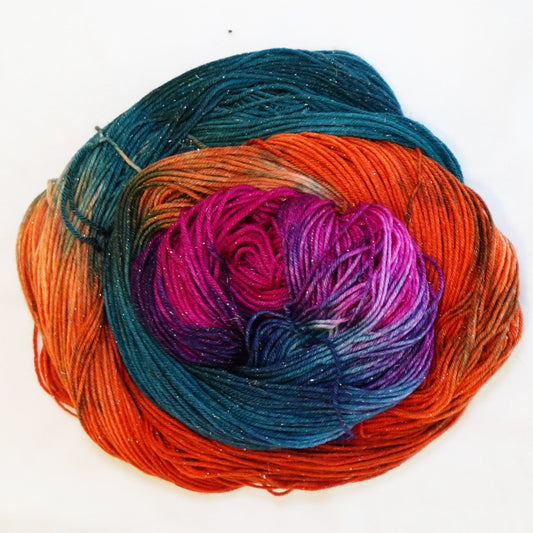 Hand-dyed gold metallic fingering weight yarn in fiery orange, deep teal, brilliant magenta and violet with a fine gold metallic thread.
