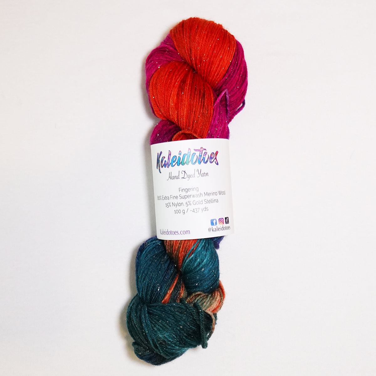 Hand-dyed gold metallic fingering weight yarn in fiery orange, deep teal, brilliant magenta and violet with a fine gold metallic thread.