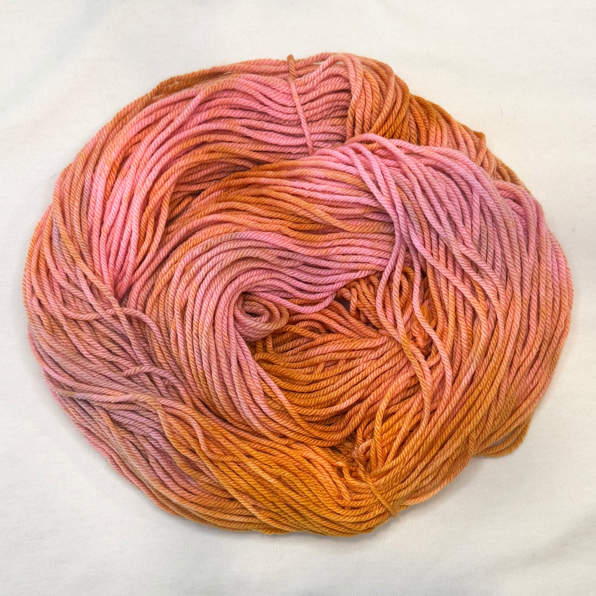 Hand-dyed yarn in shades of peach, golden amber, and blush pink — glowing softly like a sunset sky.