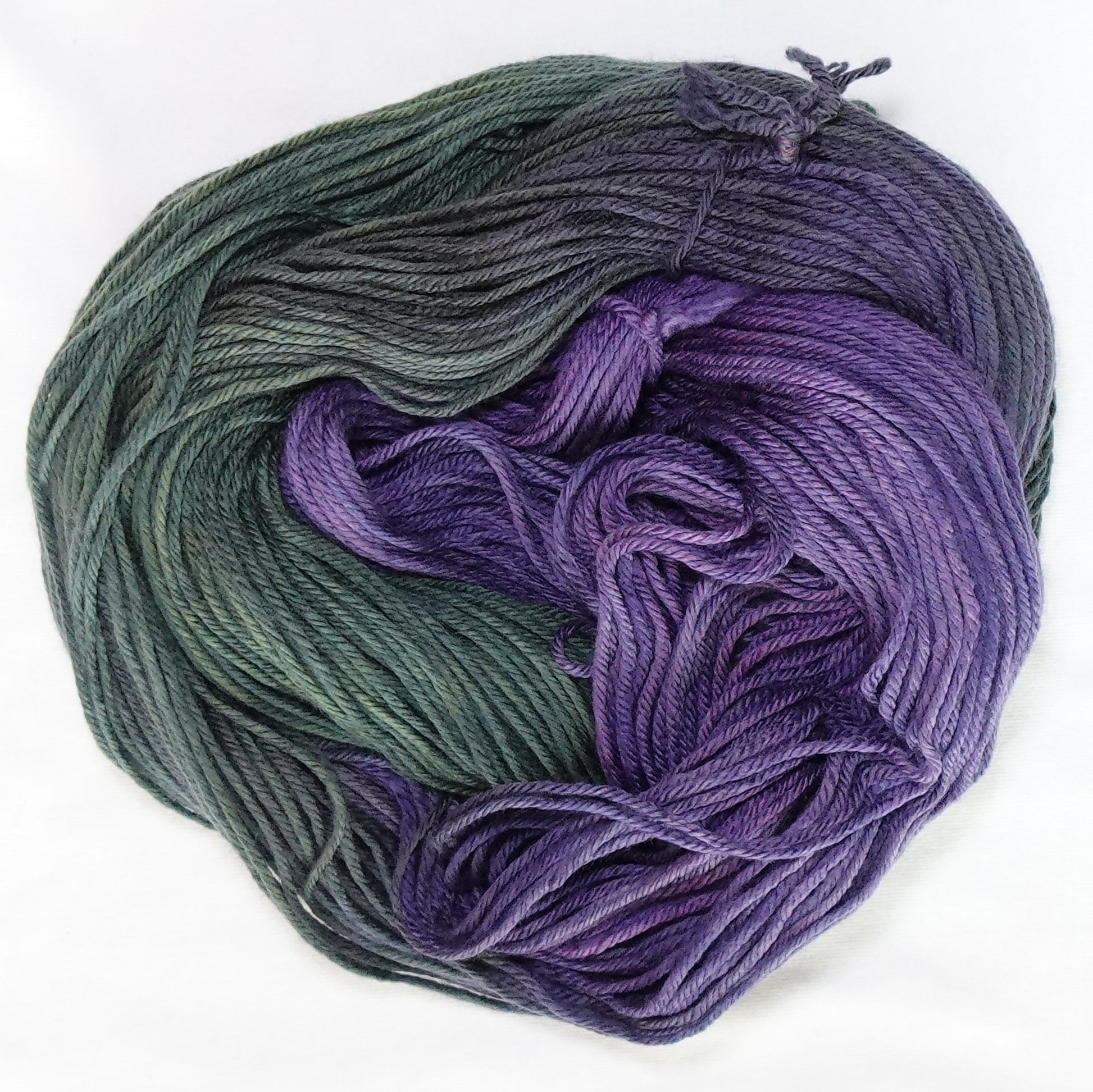 Hand-dyed worsted weight yarn in deep olive-forest green and rich violet-purple - dark, saturated, and deeply layered throughout.