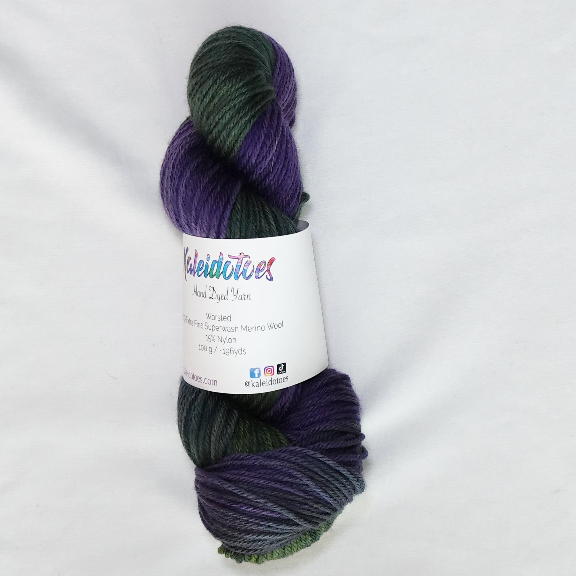 Hand-dyed worsted weight yarn in deep olive-forest green and rich violet-purple - dark, saturated, and deeply layered throughout.