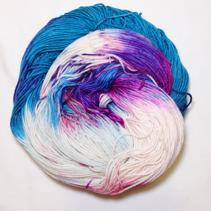Hand-dyed gold metallic fingering weight yarn in magenta, vivid violet and turquoise with white accents and a fine gold metallic thread.