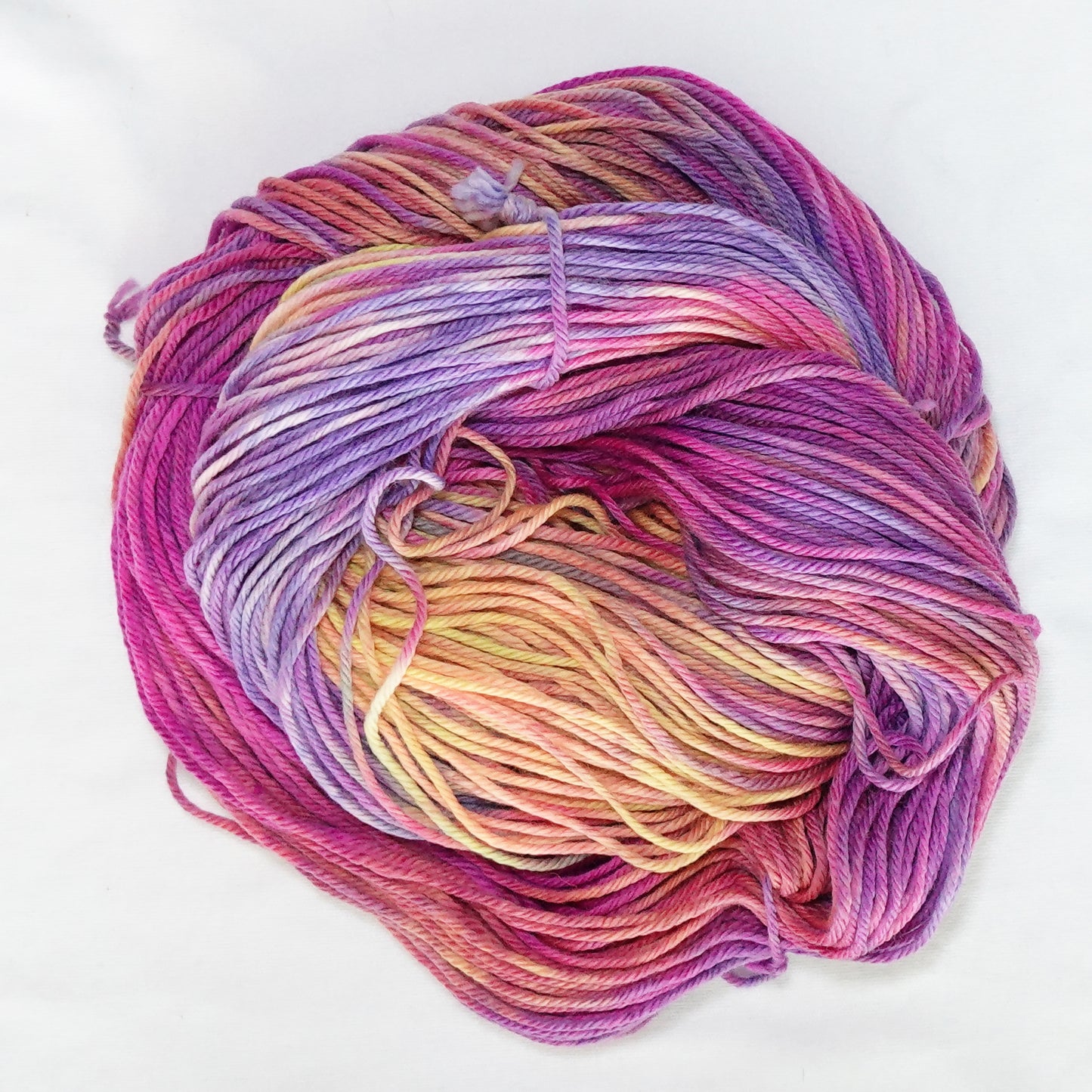 Hand-dyed worsted weight yarn in hot magenta, peach, lavender, yellow, and mauve with soft color transitions throughout.