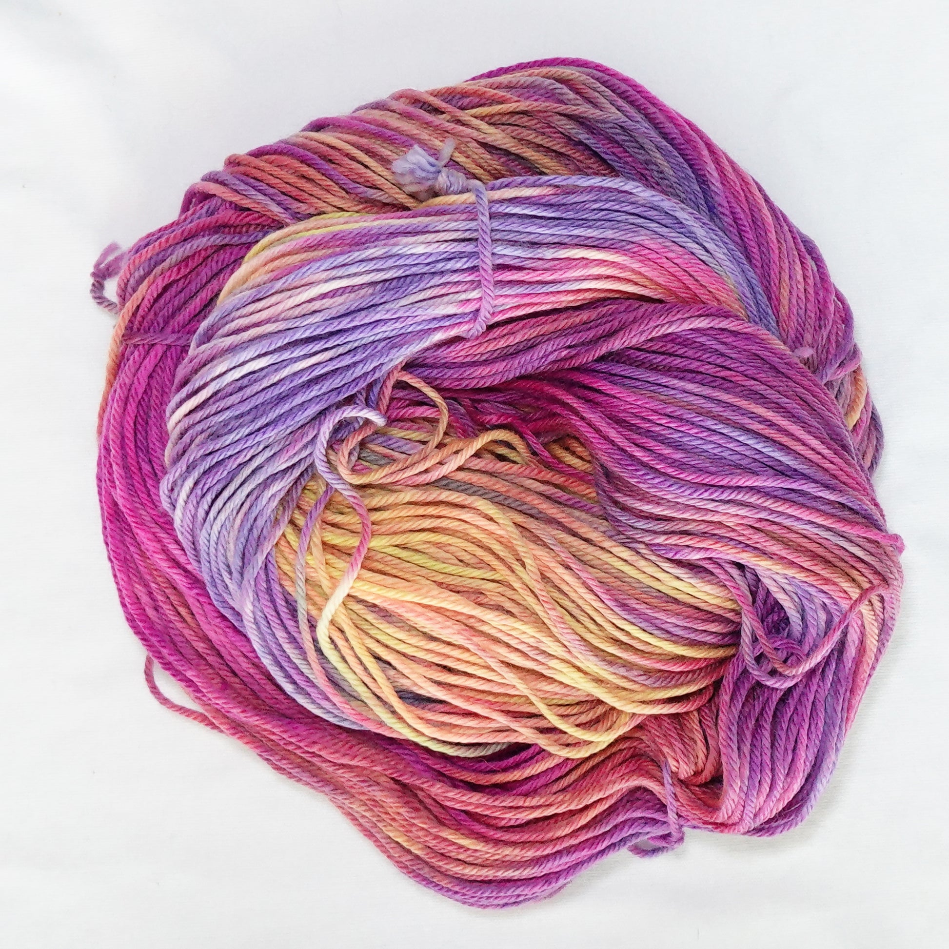Hand-dyed worsted weight yarn in hot magenta, peach, lavender, yellow, and mauve with soft color transitions throughout.