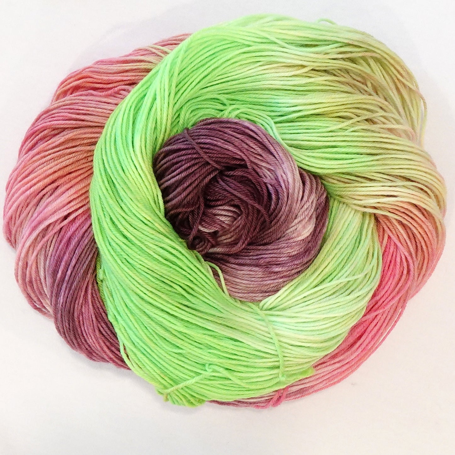 Hand-dyed fingering weight yarn in fluorescent lime green, deep burgundy, and soft coral pink with soft color transitions throughout.