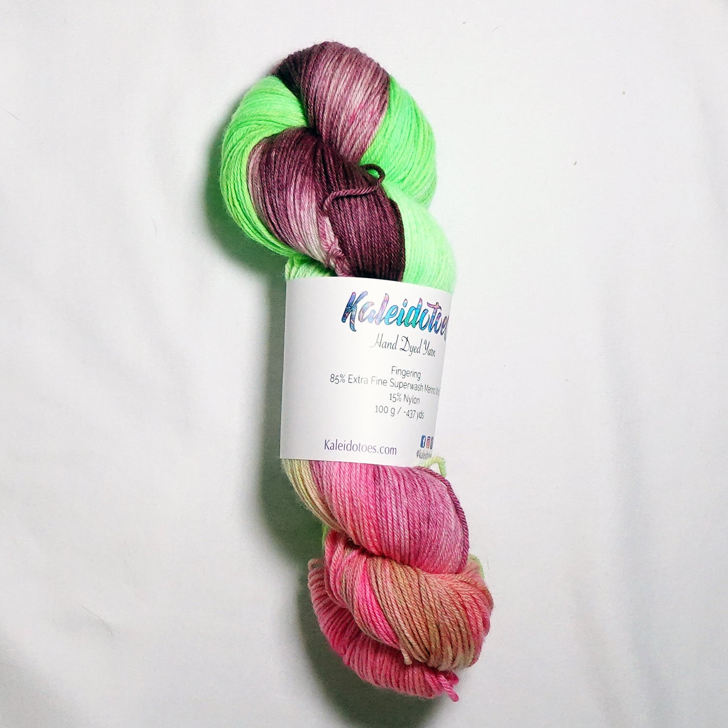 Hand-dyed fingering weight yarn in fluorescent lime green, deep burgundy, and soft coral pink with soft color transitions throughout.