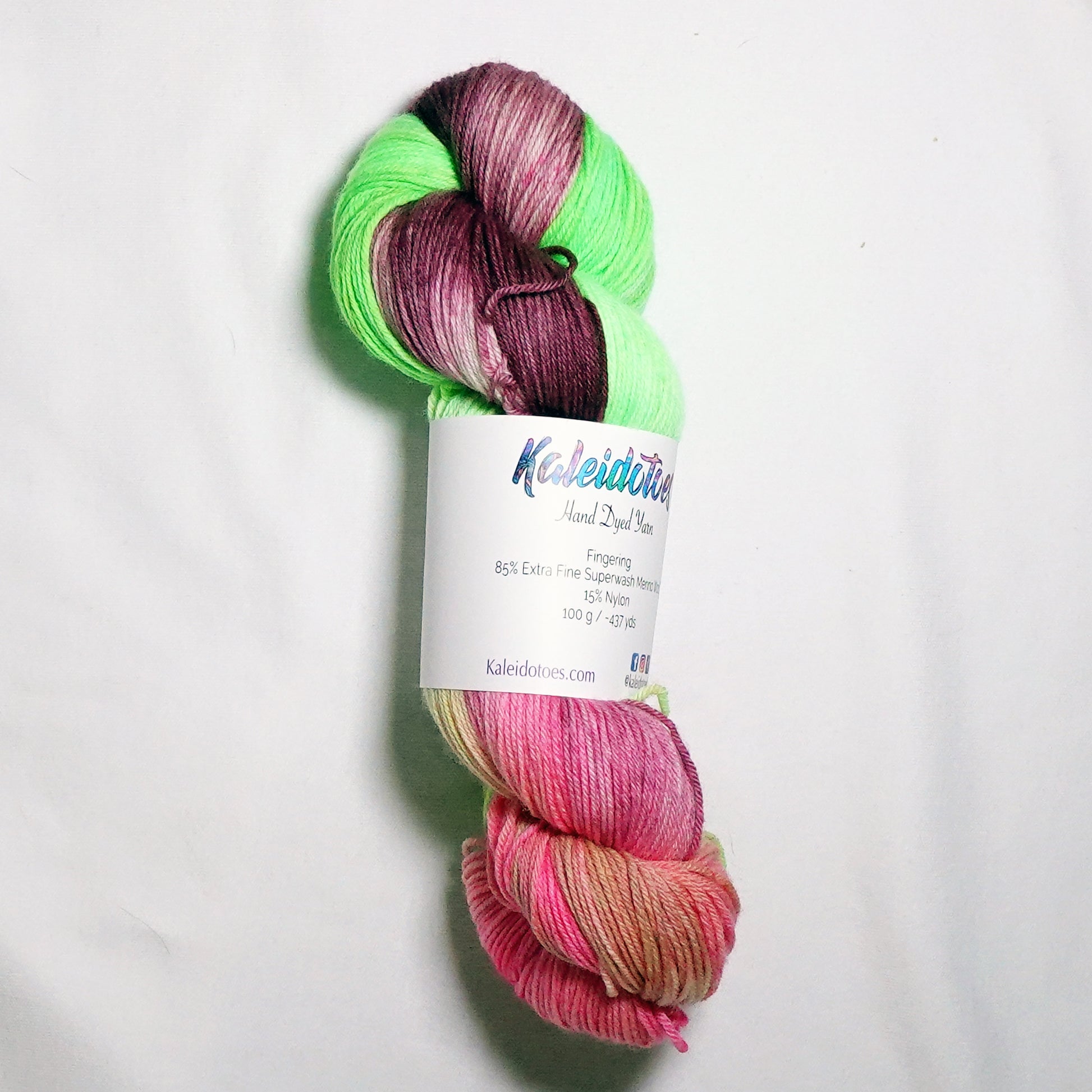 Hand-dyed fingering weight yarn in fluorescent lime green, deep burgundy, and soft coral pink with soft color transitions throughout.