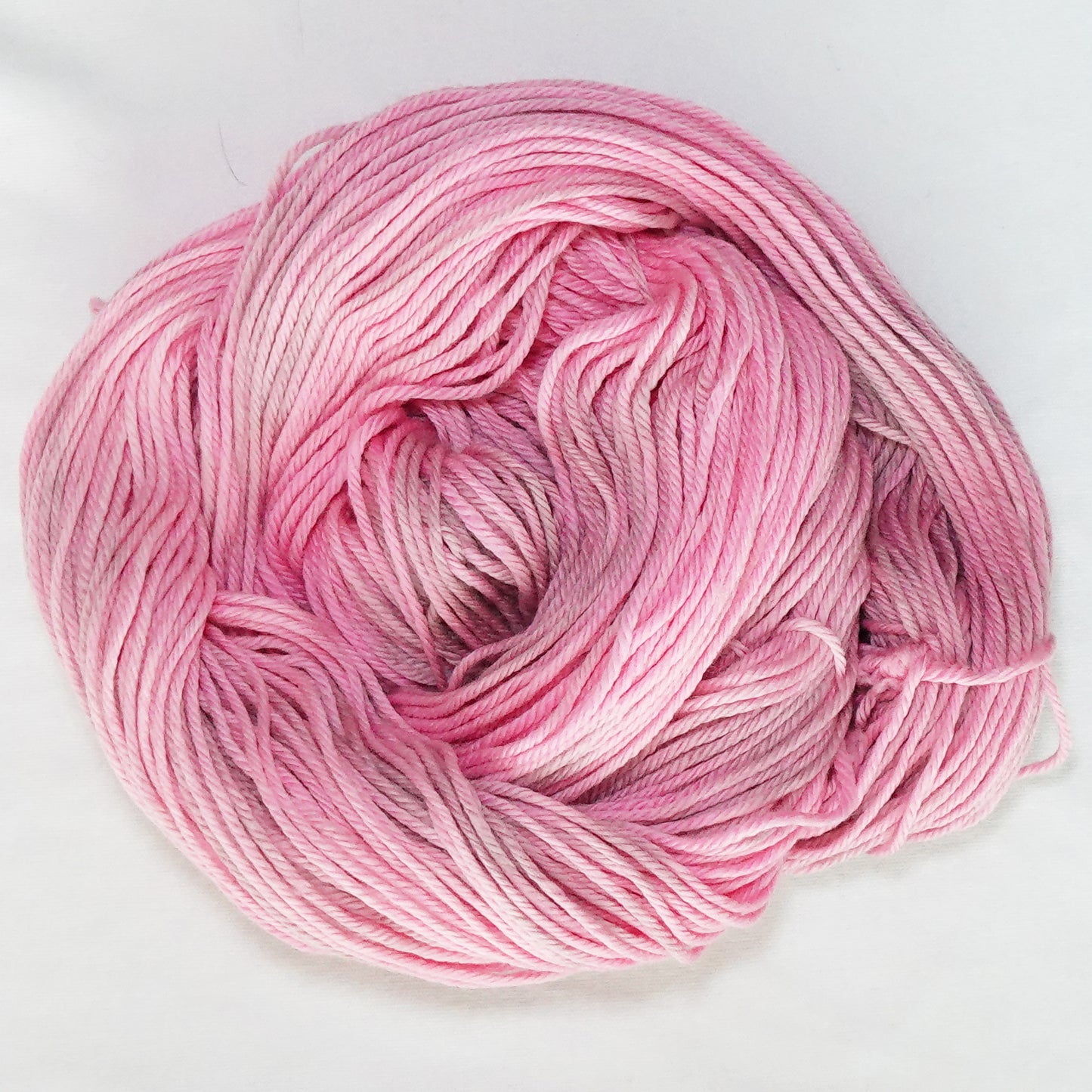 Hand-dyed worsted weight yarn in warm pink and soft taupe with subtle tonal variation throughout.