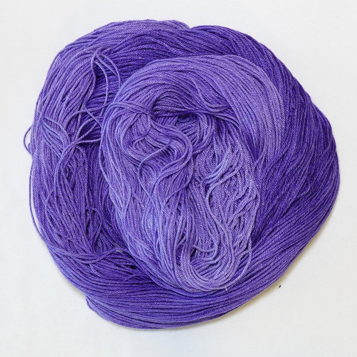 Hand-dyed fingering weight yarn in tonal purple, from deep royal violet to soft lavender.